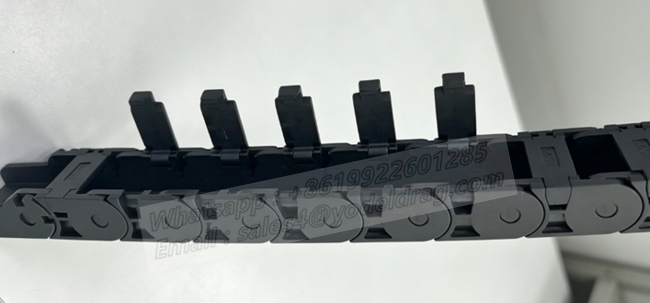 Top-angle view of a semi-enclosed PA66 small drag chain with open side latches showing the internal cable channel